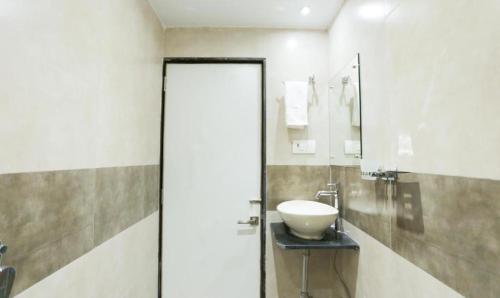 ムンバイにあるNew Amber Palace Hotelのバスルーム(白い洗面台、鏡付)