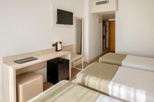 Habitación de hotel con 2 camas y escritorio en Hotel Jaime I en Salou