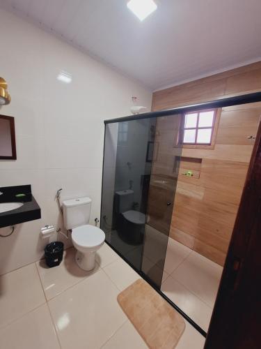 a bathroom with a toilet and a glass shower at Luar de Minas suites in Lavras Novas