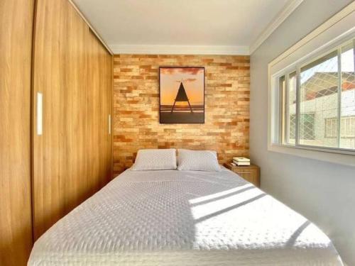 une chambre avec un lit et un mur de briques dans l'établissement Apt bem localizado centro praia box WiFi ar-condicionar, à Capão da Canoa