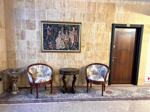 trois chaises, une table et un tableau sur un mur dans l'établissement Хотел Антик, à Pernik