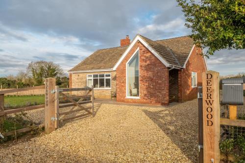 a brick house with a gate and a fence at Deerwood in Grimston