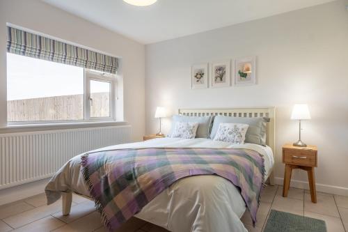 a white bedroom with a large bed and a window at Deerwood in Grimston