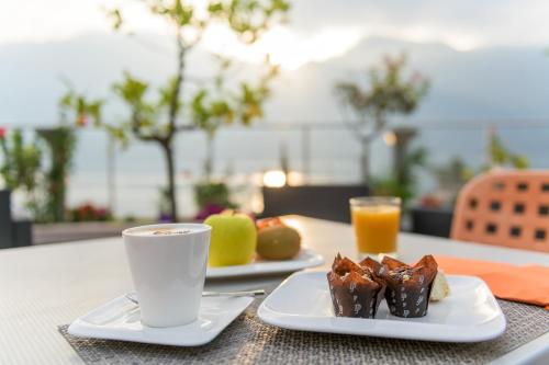 Garda Suite Hotel في ليموني سول غاردا: طبقين من الطعام وكوب من القهوة على طاولة