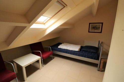 een zolderkamer met een bed en een stoel bij Schorrebloem 20* in Nieuwvliet