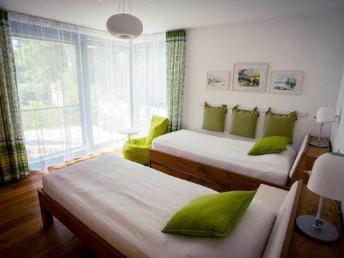 Zimmer mit 2 Betten, grünen Kissen und einem Fenster in der Unterkunft Ferienwohnung Seeufer in Kressbronn am Bodensee