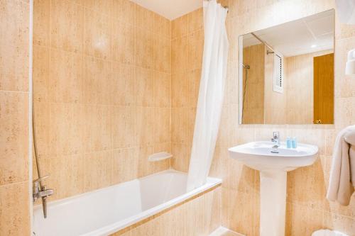 a bathroom with a tub and a sink and a bath tubermott at Hotel Jaime I in Salou