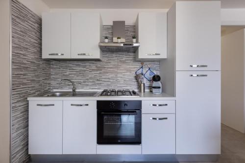 a kitchen with white cabinets and a black oven at Al civico 5 - Mondern Apartments & Suite! in Decimomannu