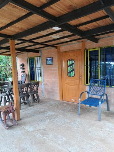 een veranda met een blauwe stoel en een houten deur bij El rincón de blanquita in Cali