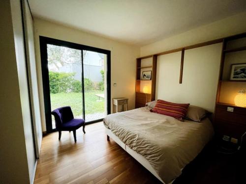 um quarto com uma cama, uma cadeira e uma janela em Ty Traezh - La plage à 100m em Santec