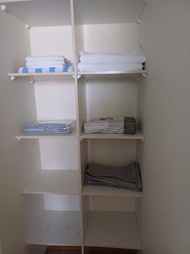 a closet with white shelves and folded towels at Depto 1 ambiente central in Antofagasta