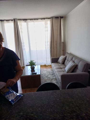 Ein Mann steht in einem Wohnzimmer mit einer Couch in der Unterkunft Depto 1 ambiente central in Antofagasta