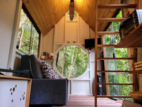 una sala de estar con sofá en una casa pequeña en Tiny House da serra perto de São Paulo em meio a natureza en Mairiporã