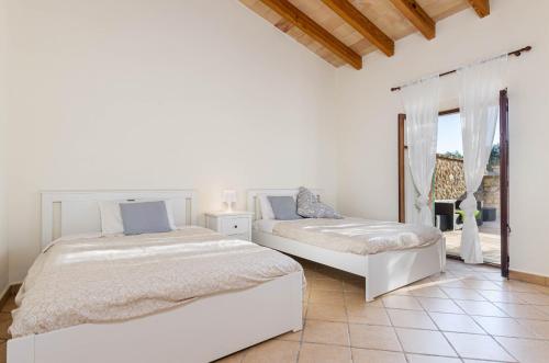 a white bedroom with two beds and a window at YourHouse Son Tey Villa in Sineu