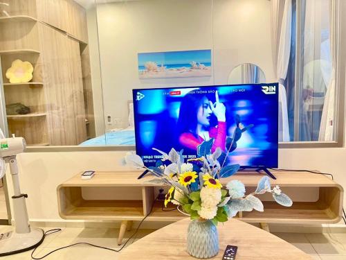 a living room with a tv and a vase of flowers at The Song Luxury Vung Tau Apartment - QUỲNH's Homestay in Vung Tau