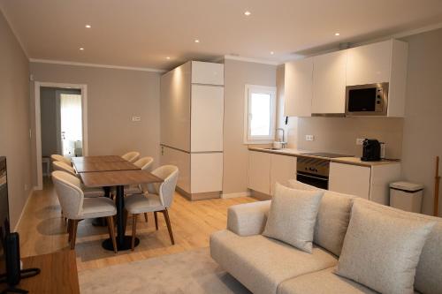 a kitchen and a living room with a couch and a table at Blank - Alojamento Local in Santo Estêvão