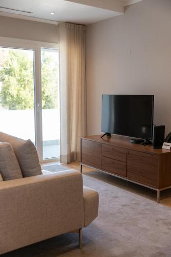 a living room with a couch and a flat screen tv at Blank - Alojamento Local in Santo Estêvão