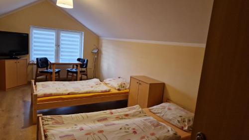 um quarto com duas camas e uma mesa e uma janela em Agroturystyka Nad Cichą em Polanica-Zdrój