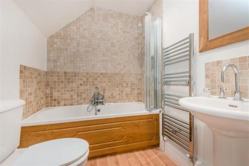 een badkamer met een bad, een toilet en een wastafel bij Revelstoke Park House in Noss Mayo