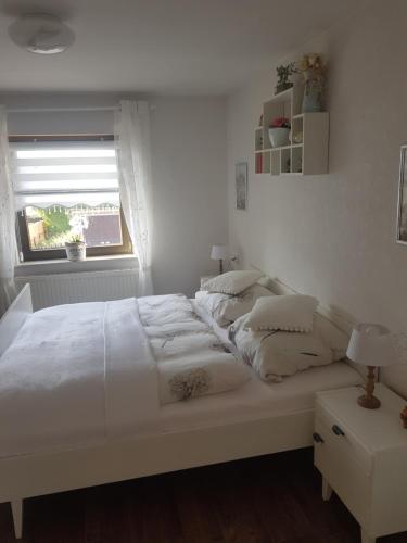 a white bed in a white bedroom with a window at FeWo Weimar in Weimar