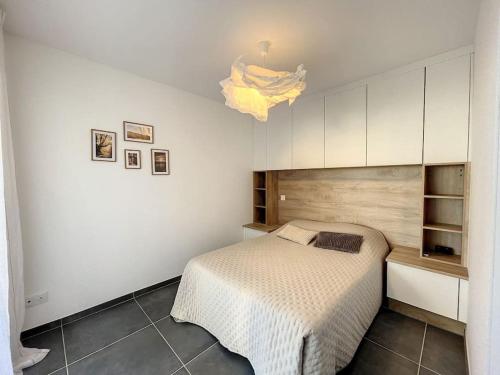 - une chambre blanche avec un lit et un lustre dans l'établissement Appartement de type T3 - Résidence avec piscine, à Calvi