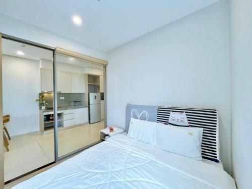 a bedroom with a large white bed and a kitchen at The Song Luxury Vung Tau Apartment - QUỲNH's Homestay in Vung Tau