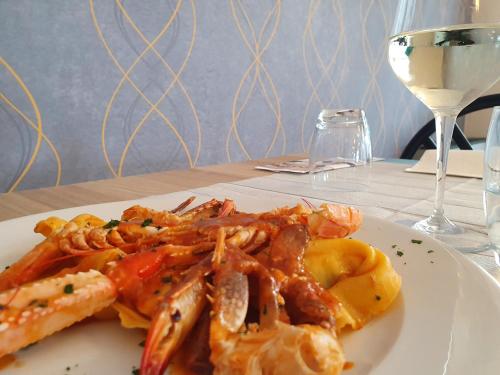 a plate of food with shrimp and a glass of wine at My Home Hotel in Bellaria-Igea Marina