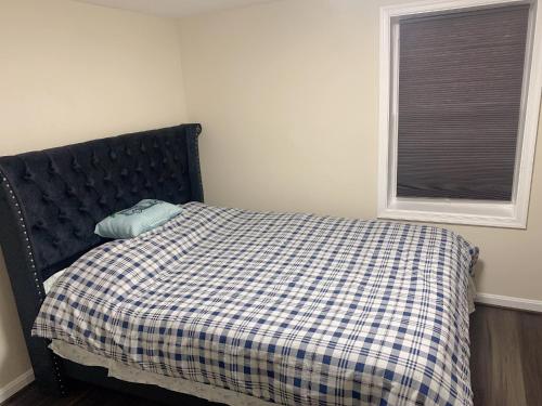 a bed with a checkered blanket and a window at Brand new en-suite private bath next Camden yard , convention center in Baltimore