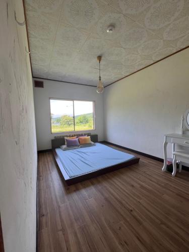 a bedroom with a bed in a room with a table at Sound Garden Biei, Cricket in Biei