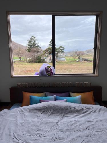 a bedroom window with a teddy bear sitting on a bed at Sound Garden Biei, Cricket in Biei