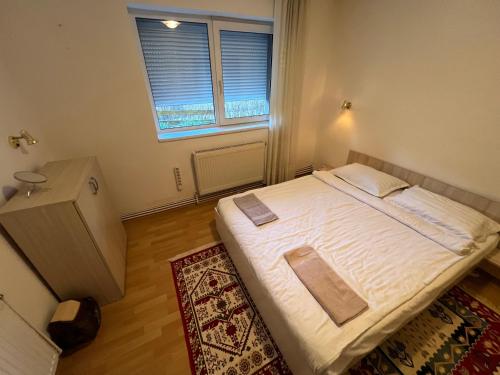 Cette petite chambre comprend un lit avec des draps blancs et une fenêtre. dans l'établissement SinaiaGateway, à Sinaia