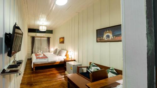a room with a bedroom with a bed and a couch at Sangthong Heritage hotel โรงแรมแสงทองเฮอริเทจ in That Phanom