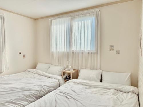 2 Betten in einem weißen Zimmer mit Fenster in der Unterkunft Stay, LoveLEE in Seoul