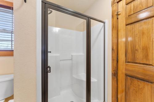 a glass shower door in a bathroom next to a toilet at Lazy JC Lodge lodge in Branson West