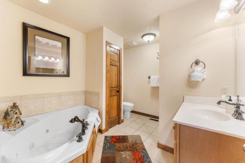 a bathroom with a tub and a sink and a toilet at Lazy JC Lodge lodge in Branson West