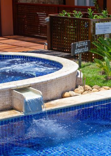 a swimming pool with a water fountain in a yard at Le Relais La Borie in Búzios