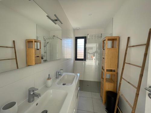 Oasis Blue Perpignan Canet في بيربينيا: حمام أبيض مع مغسلتين ومرآة