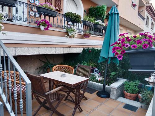 een patio met een tafel, een parasol en bloemen bij Casa La Montaña in Las Navas del Marqués