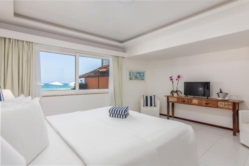 a white bedroom with a bed and a television at Le Relais La Borie in Búzios