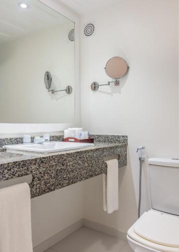 a bathroom with a sink and a mirror and a toilet at Le Relais La Borie in Búzios