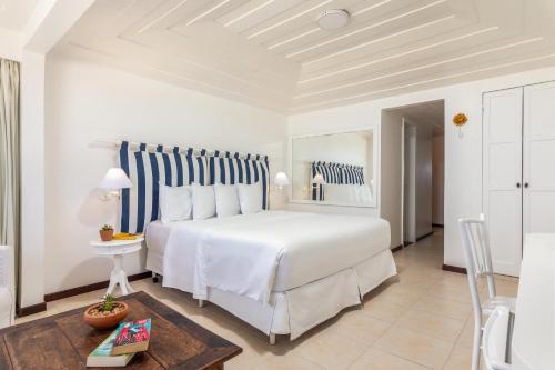 a white bedroom with a large bed and a table at Le Relais La Borie in Búzios