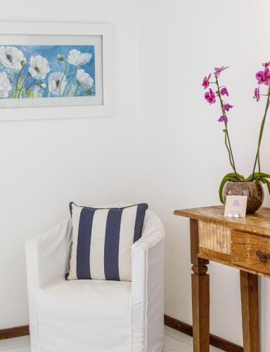 a white chair with a striped pillow next to a wooden table at Le Relais La Borie in Búzios