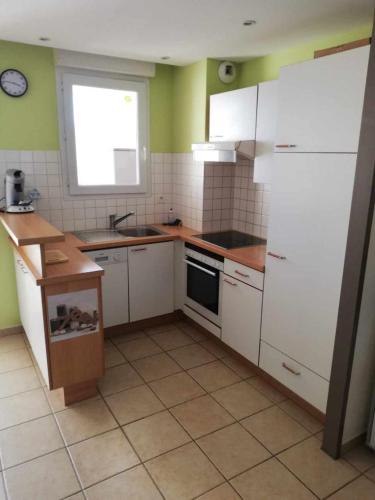 Elle comprend une petite cuisine avec des placards blancs et une fenêtre. dans l'établissement APPARTEMENT T3 AVEC TERRASSES et PISCINE SAINT CYPRIEN, à Saint-Cyprien