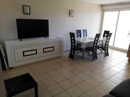 d'un salon avec une table, des chaises et une télévision à écran plat. dans l'établissement APPARTEMENT T3 AVEC TERRASSES et PISCINE SAINT CYPRIEN, à Saint-Cyprien