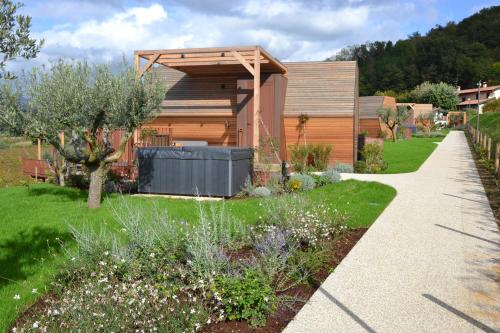 a garden with a house with a wooden structure at Glamping Alvearium Alturis in Gagliano