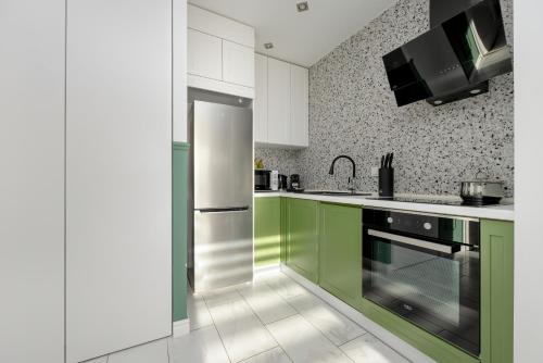 a kitchen with green cabinets and a refrigerator at Motława River Old City Gdańsk Apartment by Renters in Gdańsk