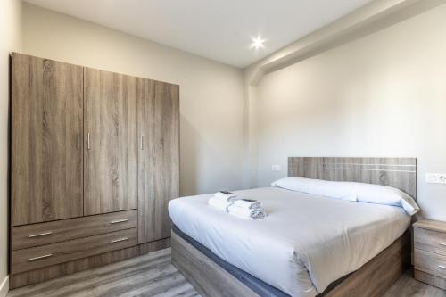 een slaapkamer met een bed en een houten kast bij Biator apartment by People Rentals in Basauri