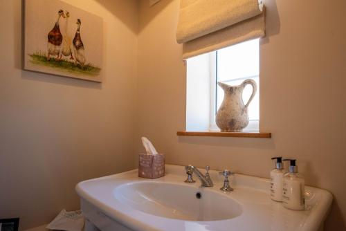 a bathroom with a sink and a window with a vase at The Borrowers in Elston