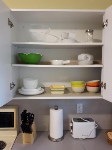 a kitchen shelf with bowls and plates and a toaster at Appartement Cartier in Longueuil