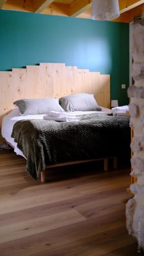 une chambre avec un grand lit avec une tête de lit en bois dans l'établissement La Char'Vigne, à Anglefort